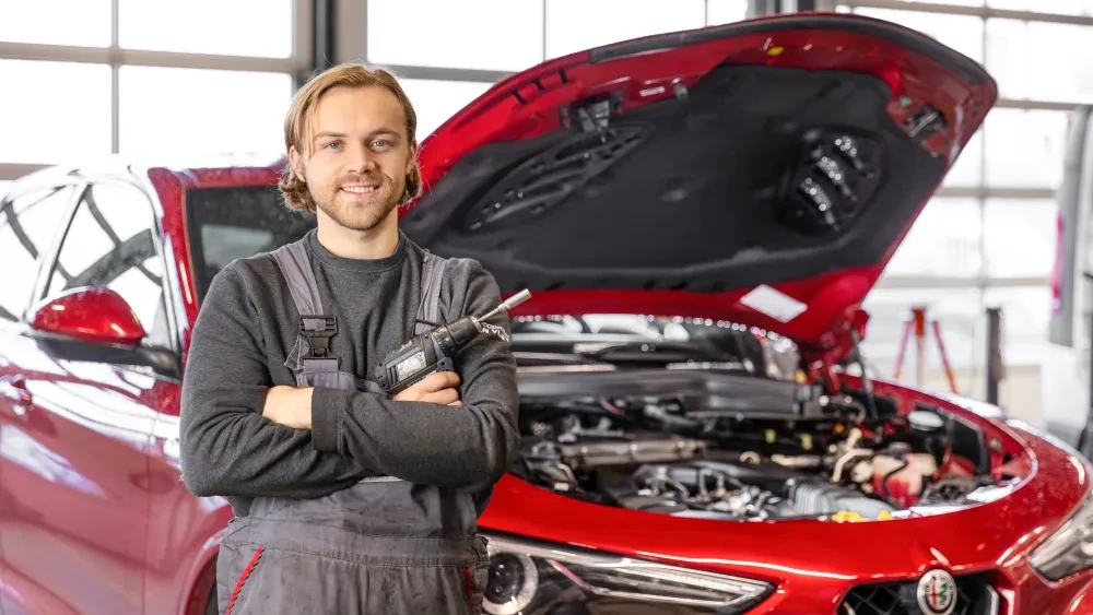 Automonteur Robbert van Dam voor een Alfa Romeo met motorkap open